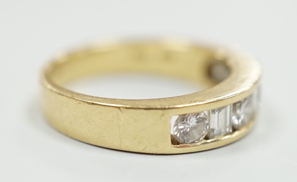 An 18k yellow metal, four stone round cut and three stone rectangular cut channel set diamond half hoop ring, size L, gross weight 4.9 grams.